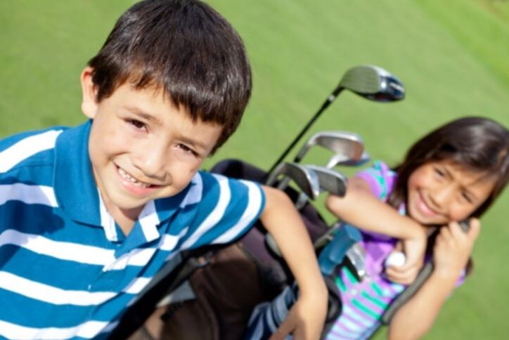 Kids smiling next to golf bag